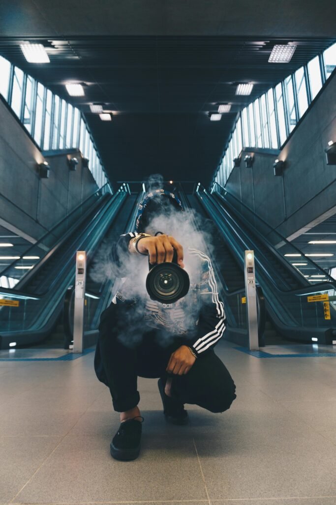 pexels-photo-598917-598917 Person holding a camera in a smoke-filled urban setting with escalators.